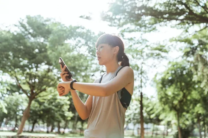 Asian sportswoman using smart watch and smartphone during
